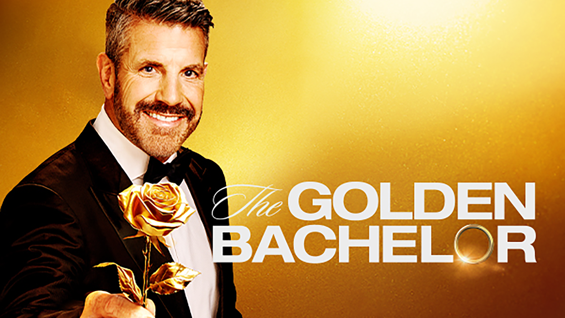Smiling bearded man in a tuxedo beside “The GOLDEN BACHELOR” title on a golden background.