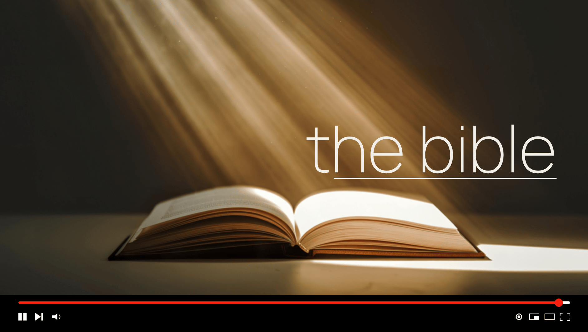 Open Bible illuminated by diagonal golden light, with “the bible” written in large white text above it.